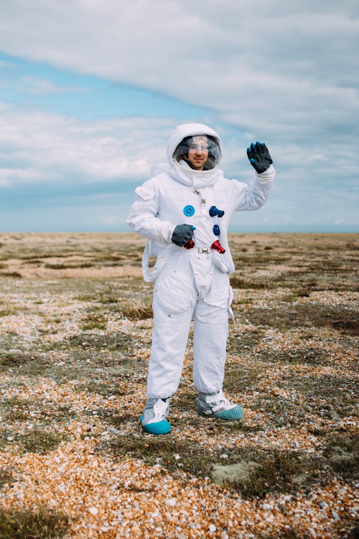 about-us Person in astronaut suit standing on a rocky terrain under a blue sky.